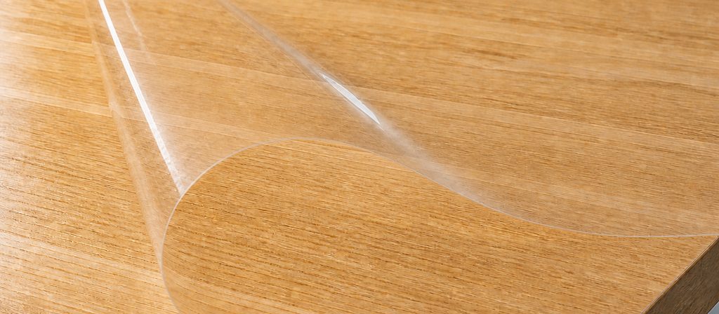 Película protectora transparente levantada sobre un tablero enchapado en madera