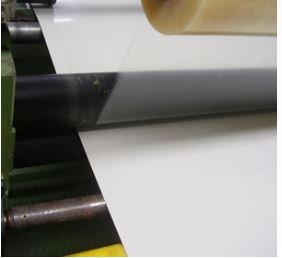 Máquina laminadora aplicando película protectora sobre una lámina